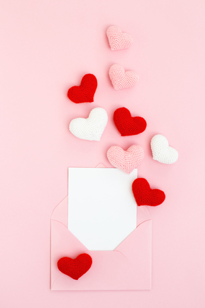 Happy Valentine's Day card in envelope with pink, white & red spreading hearts on pink background. Holiday Congratulation. Romantic Love message. Flat lay, vertical.の写真素材