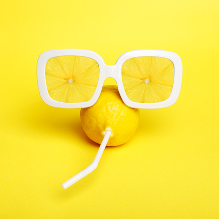 Tropic Lemon in vintage sunglasses with lemon slices reflection. Minimal fashion summer mood concept. Trendy monochrome yellow.の写真素材
