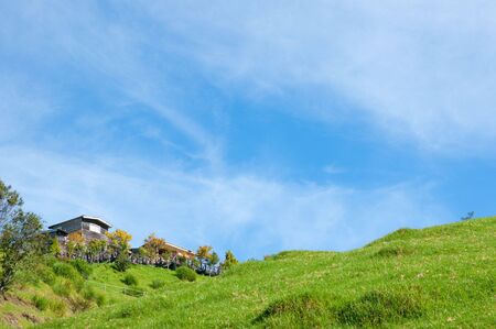 House on the mountain with blue sky and green grasses.の写真素材