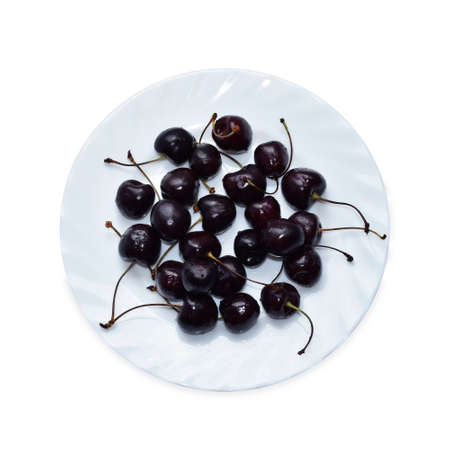 Sweet black cherry on a plate on white background. Berries top view isolated. Vitamins, vegetarian food, organic dietの写真素材