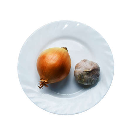 Onion and garlic on a plate isolated. Antibacterial vegetables on white background. Prophylactic of a cold, healthy organic foodの写真素材