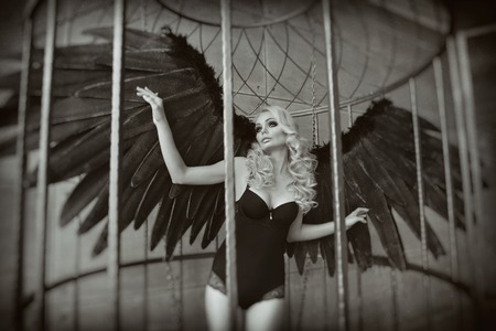 blond woman with black wings in a cage.の写真素材