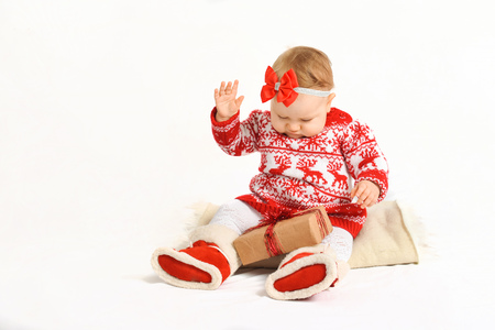 baby in a Christmas costume sits with gifts. beautiful New Years presentsの写真素材