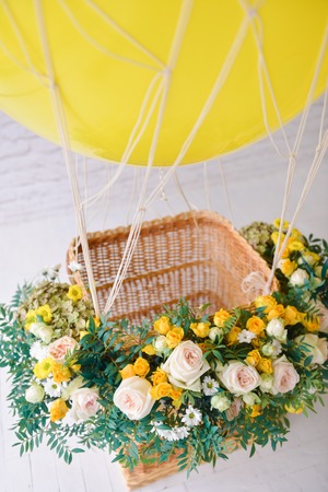 balloon with a basket decorated with live flowers, as a festive props for a childrens holiday birthday of yellow. close-up, detailsの写真素材