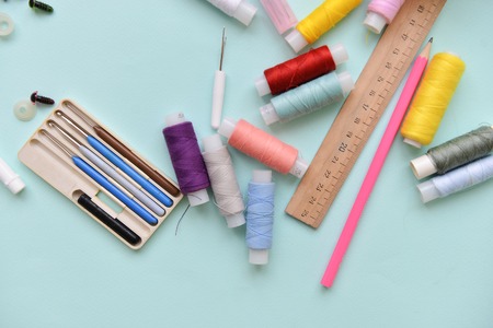 sewing accessories for needlework threads different colors ruler, crochet hooks and needles lie on isolated blue background.の写真素材