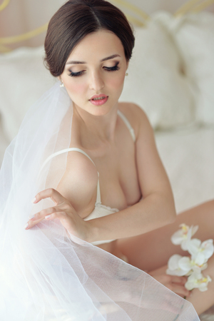 Young attractive female model girl before the wedding. Morning boudoir of the bride. Beautiful lingerie and dress, delicate imageの写真素材
