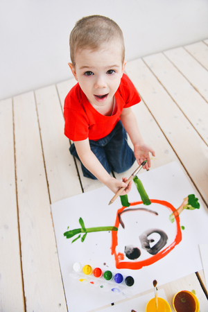 creative children paint brush paints on paper funny colorful pictures on a floor, art in a group art school. in a creative search for emotionの写真素材