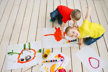 creative children paint brush paints on paper funny colorful pictures on a floor, art in a group art school. in a creative search for emotionの写真素材