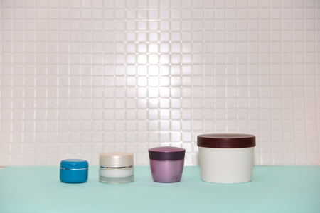 Set various multicolored plastic cosmetic cream jars on shelf in bathroom.の写真素材