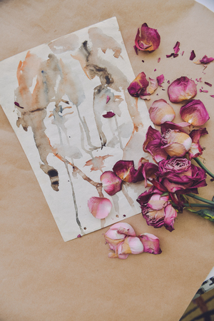 portrait sad weeping woman with watercolors kraft paper background dry faded red roses. Concept psychology, depressive state, anti-valentin day, unrequited love, psychotherapy. small noiseの写真素材
