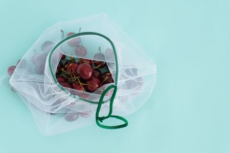 cherry in a reusable fabric transparent bag on a blue background in the fight against plasticの写真素材