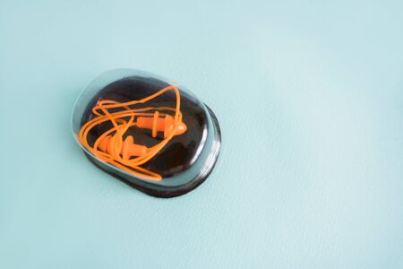 pair of orange rubber earplugs in the form of spruce lie in a box on a blue backgroundの写真素材