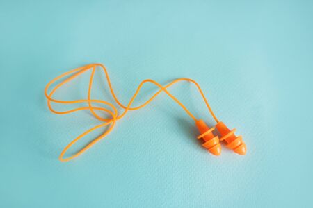 pair of orange rubber earplugs in the form of spruce lie on a blue backgroundの写真素材