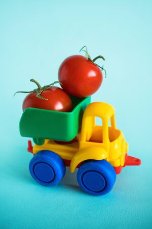 tomatoes natural vitamins are in the back of truck in a childrens toy car food delivery truck logisticsの写真素材