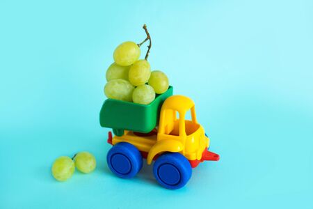 grapes natural vitamins are in the back of truck in a childrens toy car food delivery truck logisticsの写真素材