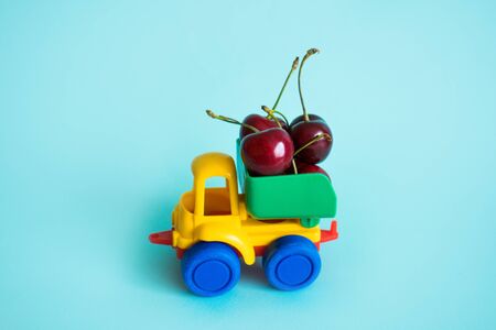 cherries natural vitamins are in the back of truck in a childrens toy car food delivery truck logisticsの写真素材