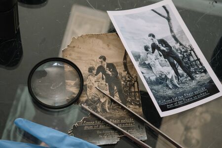 Belarus, Soligorsk, July 1, 2019: mastery of restoring old vintage damaged photos of close-up specialist working place with a pair of tweezers with a magnifying glass and glovesのeditorial素材