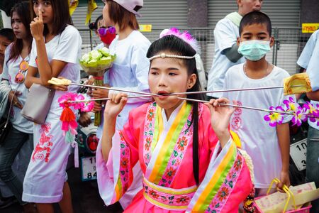 Thailand, Phuket, October 7, 2019: Closeup portrait of a young beautiful Thai girl of Chinese descent with a pierced metal knitting needle on her cheek at celebration of a festival of vegetariansのeditorial素材