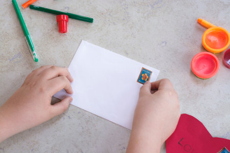 Kid playing with white envelope and post stamp. Kids art. Crafts concept.の写真素材