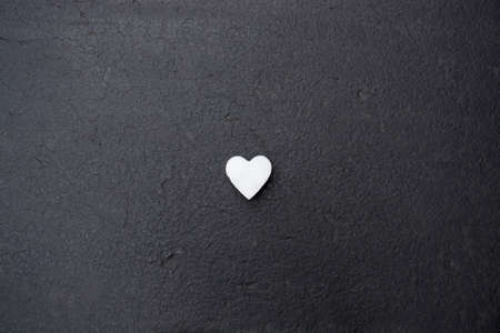 White hearts made of snow laying on black concrete background surface. Flat lay, Top view.