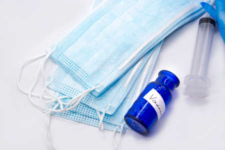 Vaccine vintage bottle, medical protective blue masks and gloves on white
