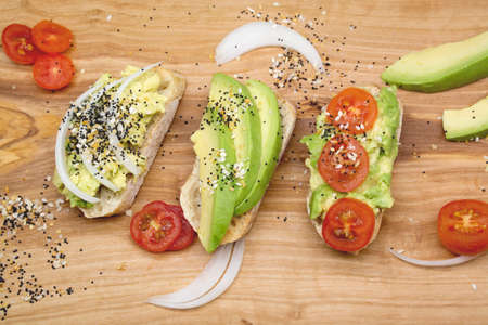 Variety of sandwiches for breakfast, appetizers with seeds and tomatoes on wooden board, dark...