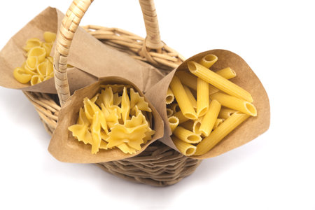 pasta in paper bags in wicker basket isolated on white background. No plastic content. Replacing plastic bag. Eco package conceptの写真素材