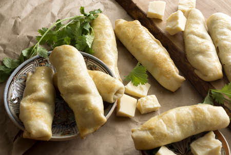 stuffed roles, home made stuffed pastries, pieces of cheese and blackberry. Delicious pastries on wooden cutting board.の写真素材