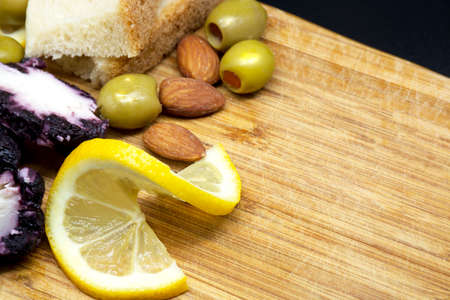 cheeses, lemon, nuts and olives on light wooden cutting board. Serving antipasto on older wooden chopping board.の写真素材