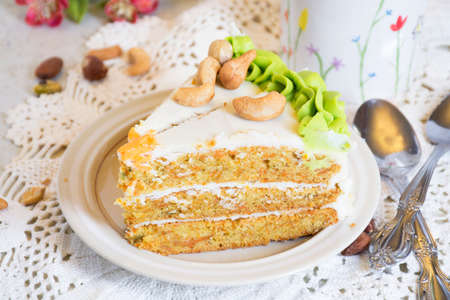 Slice of homemade carrot cake with cream cheese frosting on white plate.の写真素材