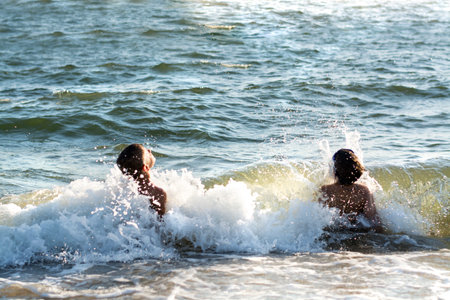 kids having fun in ocean waves. Excited children playing with water, swimming, splashing. Summer Sunny Day, Ocean Coastのeditorial素材