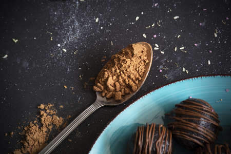 cocoa powder in spoon, chocolate truffles on blue plateの写真素材