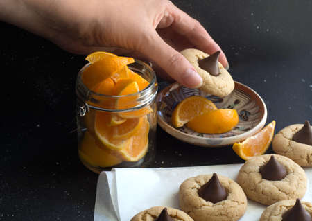 cookies with chocolate candy kiss, sliced orange pieces, hand taking cookieの写真素材