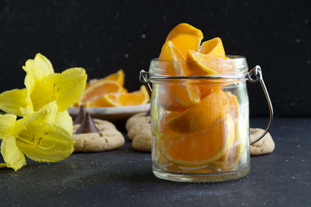 Orange fruit slices in glass jar on dark background. Healthy living conceptの写真素材