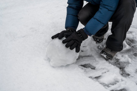 Boy makes big snow ball. Child playing with snow. Winter time outdoor funの写真素材