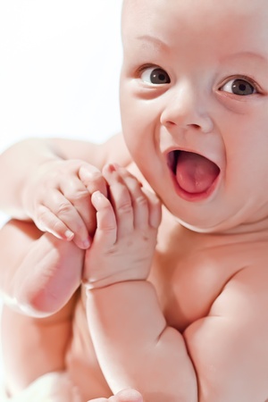 Happy baby playing with hands and legs on white backgroundの写真素材