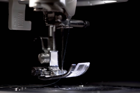 Sewing machine part with needle closeup on white background