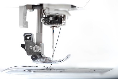 Sewing machine part with needle closeup on white background