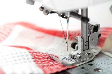 Sewing machine closeup with red fabric on white backgroundの写真素材