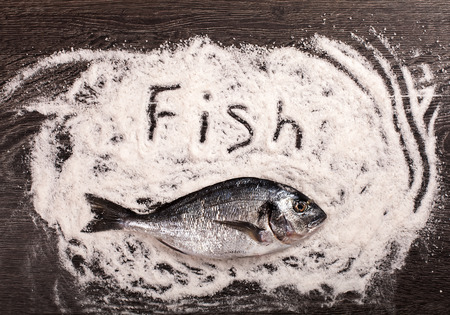 Fresh dorado fish on salt and dark wooden backgroundの写真素材