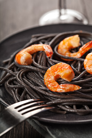 Black italian pasta with shrimps food on dark backgroundの写真素材