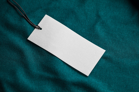 Clothes label tag on dark color cloth background blank white branding template mockupの写真素材