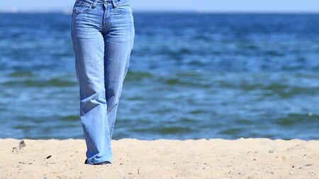 Legs of a young woman walking along the seacoastの写真素材