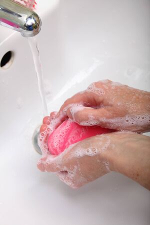 Woman wash red soapy hands in bathroom soapの写真素材