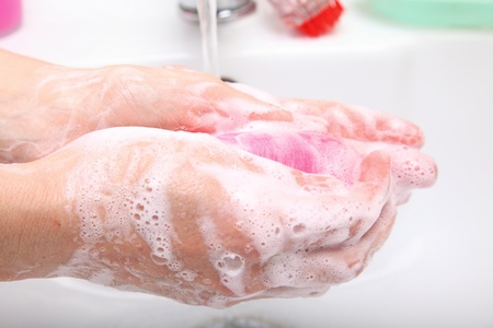 Woman wash red soapy hands in bathroom soapの写真素材