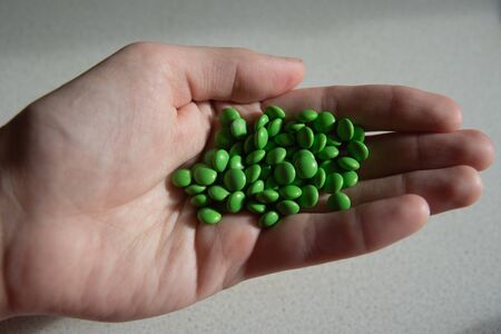 A lot of green pills in handの写真素材