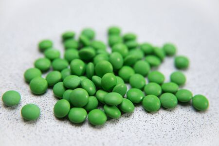 a scattering of green tablets pills on a white backgroundの写真素材