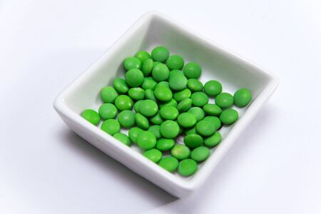 Many green pills in a white square cupの写真素材