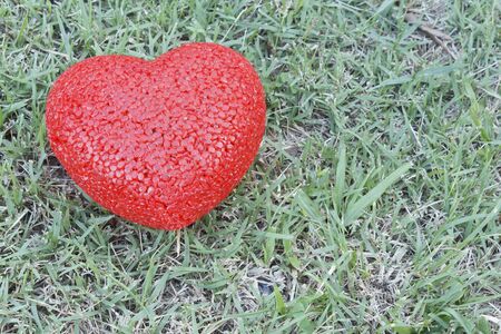 Plastic red heart shape on nature green grass backgroundの写真素材