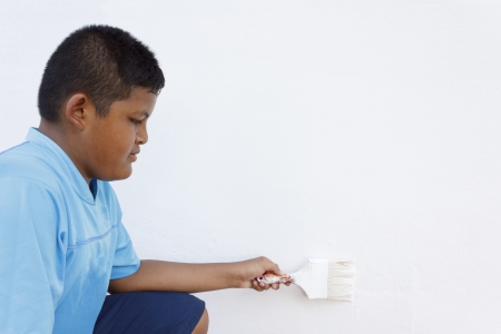 Thai boy painting the wall white with a paint brushの写真素材
